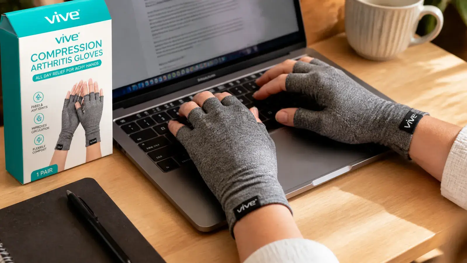 Hands wearing open-finger compression gloves at a laptop keyboard, the gloves visibly riding up past the wrist toward the lower forearm during typing
